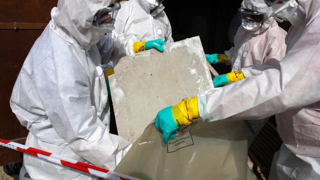 Four people in hazmat suits removing asbestos