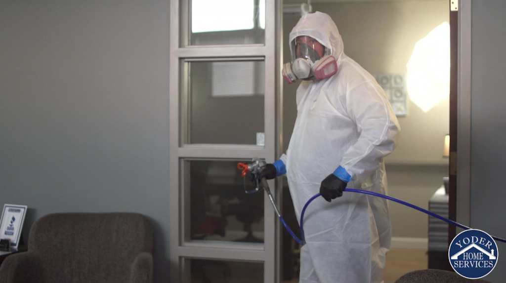 Man in white protective suit sprays disinfectant at TJ21 Media Group
