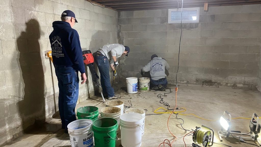 Jerry yoder and two employees in sweatshirts work on repairing a concrete foundation