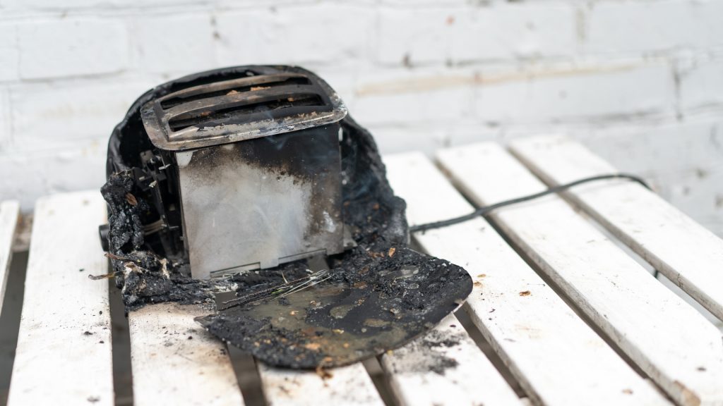 A burnt toaster on a white plywood table