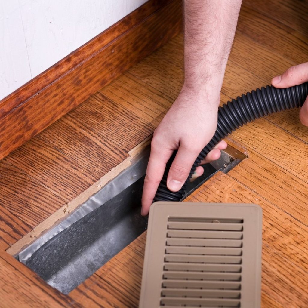 Man uses vacuum cleaner to clean air ducts